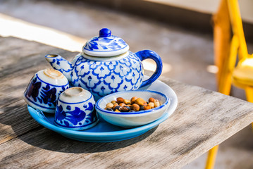 Set of Asian blue and white ceramic teapot and tea cups with snacks on wooden table