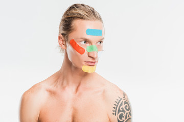 naked handsome man with multicolored patches on face isolated on white