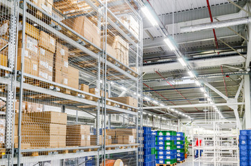 Large cardboard boxes on shelves closed metal mesh in a warehouse in an industrial enterprise. Warehouse technologies, employment at the factory. Arrangement of goods. Parcel delivery.