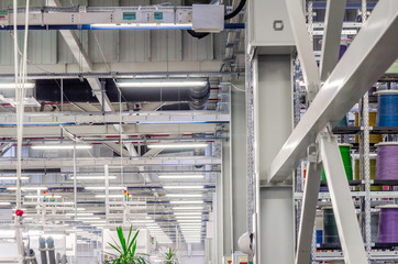 interior of a large industrial workshop, luminescent lamps under the ceiling are suspended in rows. Working atmosphere.