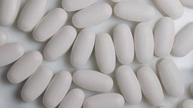 Pills rotate on white background. Medicine, sport supplement, creatine, hmb, bcaa, amino acid or vitamin pill.