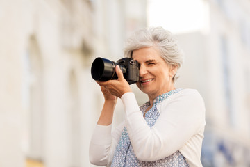 old age, photography and people concept - happy senior woman photographing by digital camera on city street