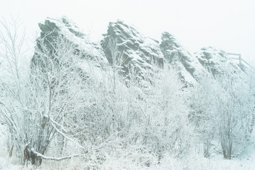 beautiful snow-covered rocks over the winter forest during a snowfall