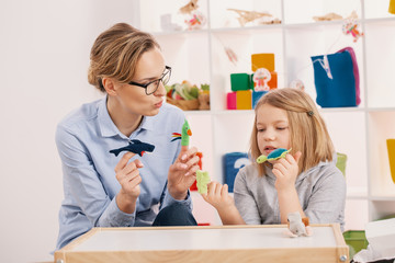 Mother holding toys while playing with daughter at girl's room