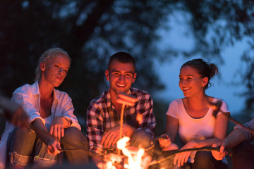 young friends relaxing around campfire