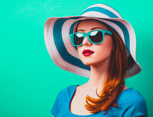 style redhead girl with makeup in blue hat and sunglasses on green background isolaed