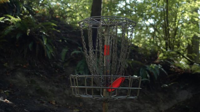 Orange Frisbee Disc Slow Motion in Forest Golf Basket