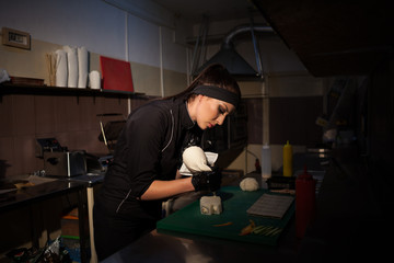 beautiful woman chef prepares sushi on restaurant kitchen