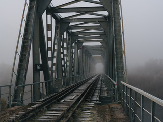 old railway bridge in the early foggy morning. terrible place