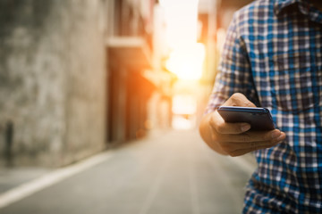 Close up of businessman or backpack checking email and searching map mobile phone in  the old street town,copy space.