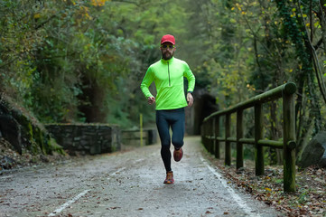 Fototapeta premium Man athlete runs on bicycle lane in the fall