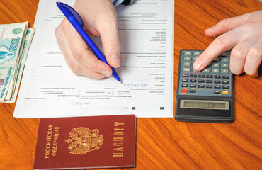 The man fills in the tax return, calculates the amount of tax on the calculator,