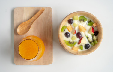 Fruit salad with yogurt on a wooden bowl and orange juice