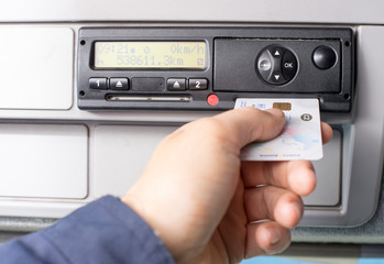 Digital tachograph and drivers hand inserting the digital card in the slot for the second driver