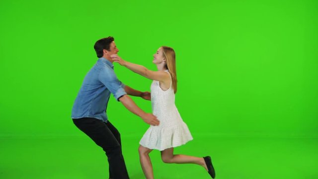 A in love man and a woman running to each other, hugging and spinning happily in slow motion over a green screen.