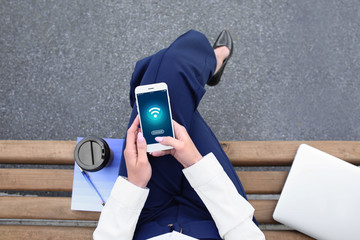 Young woman with mobile phone resting on bench outdoors