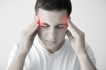 Fototapeta premium Young man suffering from headache on light background