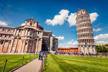 Beautiful spring view of famous Leaning Tower in Pisa. Sunny morning scene with hundreds of tourists in Piazza dei Miracoli (Square of Miracles), Italy, Europe. Traveling concept background.