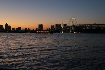 Obraz premium View from Odaiba Beach to Tokyo Bay with Rainbow Bridge at dusk, Tokyo, Japan