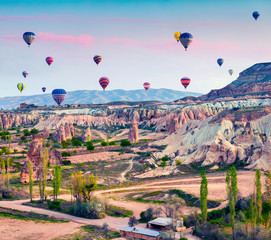 Flying on the balloons early morning in Cappadocia. Colorful spring sunrise in Red Rose valley, Goreme village location, Turkey, Asia. Traveling concept background.