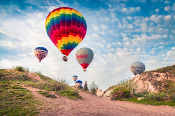 Flying on the balloons early morning in Cappadocia. Colorful spring scene of Red Rose valley, Goreme village location, Turkey, Asia. Traveling concept background.