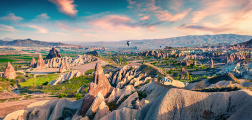 Unreal world of Cappadocia. Colorful sunrise in Red Rose valley in April. Cavusin village located,...