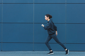 active adult sportswoman jogging in sportswear near building