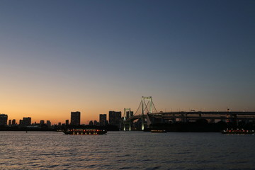 View from Odaiba Beach to Tokyo Bay with Rainbow Bridge at dusk, Tokyo, Japan