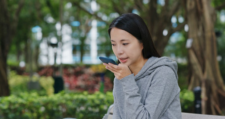 Woman send audio message in city park