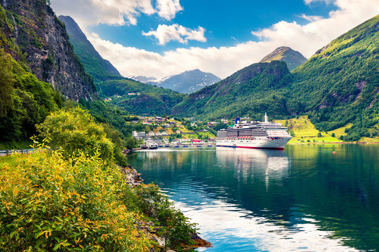 Sunny summer scene of Geiranger port, western Norway. Colorful view of Sunnylvsfjorden fjord. Traveling concept background. Artistic style post processed photo.