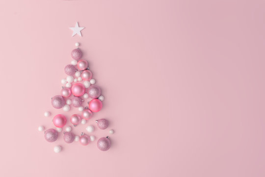 Christmas composition. Christmas tree made of pink ball decoration on pink table background. Flat lay, top view, copy space. New Year sale card.