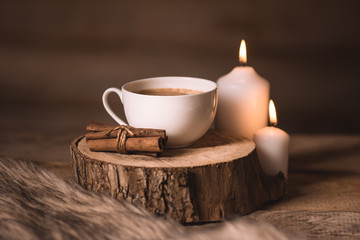 white cup of coffee, candles, cinnamon and fur 