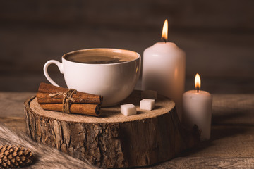 white cup with coffee, candles, sugar, cinnamon, pinecone and fur 