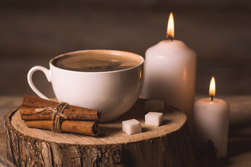white cup with coffee, candles, sugar and cinnamon