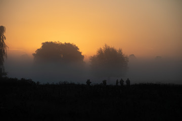 Silhouette of photographers during misty sunrise