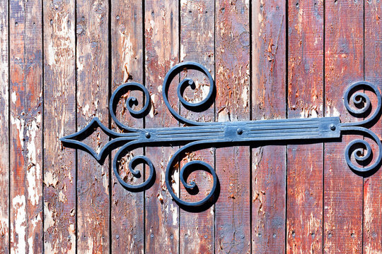 Forged openwork Arrow on an old wooden door.