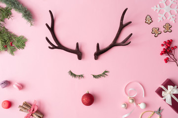Christmas reindeer concept with presents, decoration, and winter things on pastel pink background....