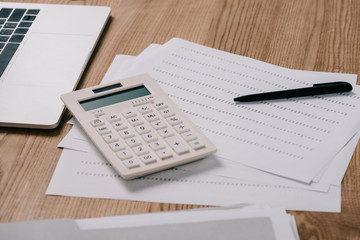 close up view of workplace with calculator, laptop, pan and notebook