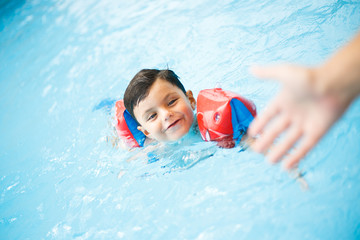 Funny little boy swims in a pool