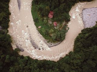 Rain forest River in Indonesia threatening to flood Huts. Drone Shot.