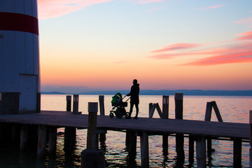 Lighthouse pier with stroller walking woman silhouette on awesome sunset sky background over the lake, Podersdorf Lighthouse, Neusiedl see in Austria