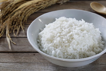 Jasmine rice in  bowl and paddy rice on a brown wooden background beautiful Thai food