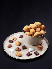Walnut shaped cookies on a plate, with bits of chocolate, heart shaped sugar cubes and walnuts. Russian oreshki.