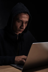 hacker in black hoodie using laptop, cuber security concept
