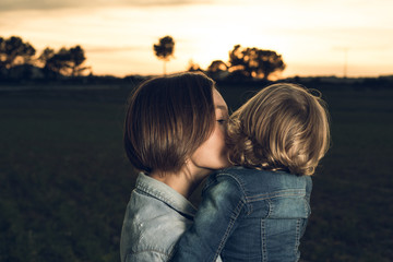 Close-up of a mother hugging her little daughter at sunset