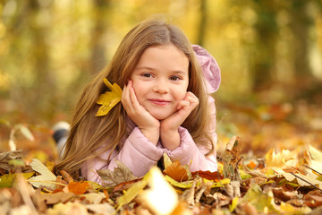 Hübsches kleines Mädchen liegt im Herbstlaub und lacht