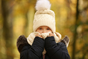 Kleines Mädchen in Winterkleidung schaut zieht einen Schal vor das Gesicht