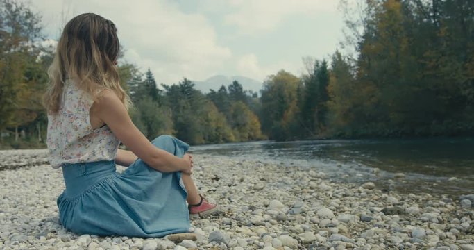 Young woman sitting by river in forest