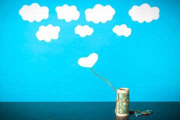 a heart connected with money trying to fly away into the clouds