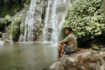 Fototapeta na wymiar young male sitting looking at the waterfall